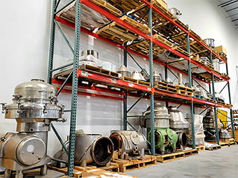 Assorted centrifuge parts on metal shelving in warehouse